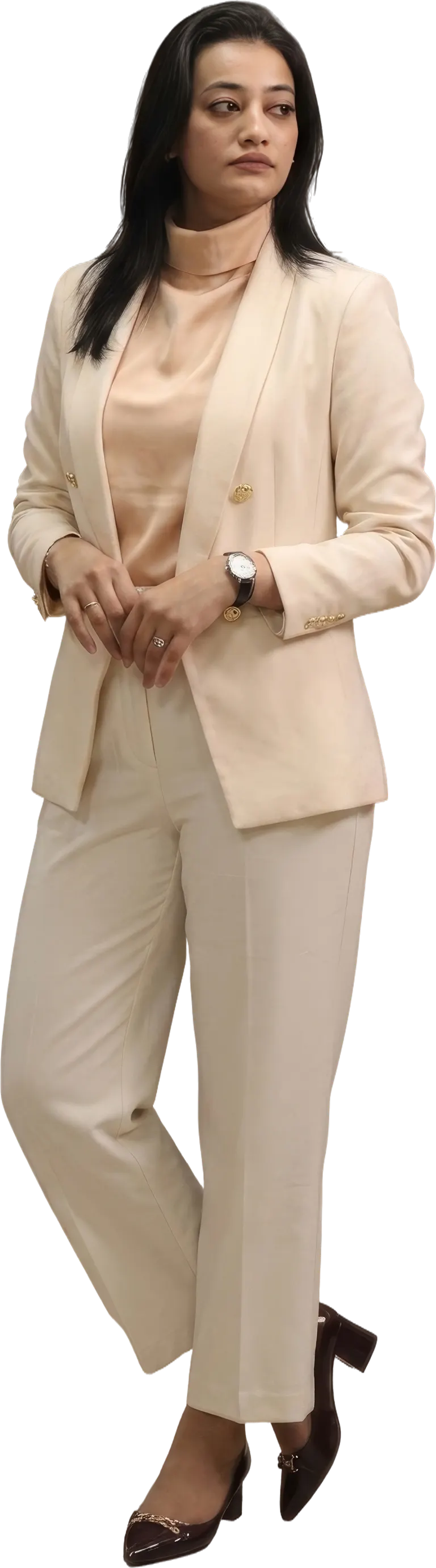 A young woman mid-step in a cream trouser suit, hands held in front of her